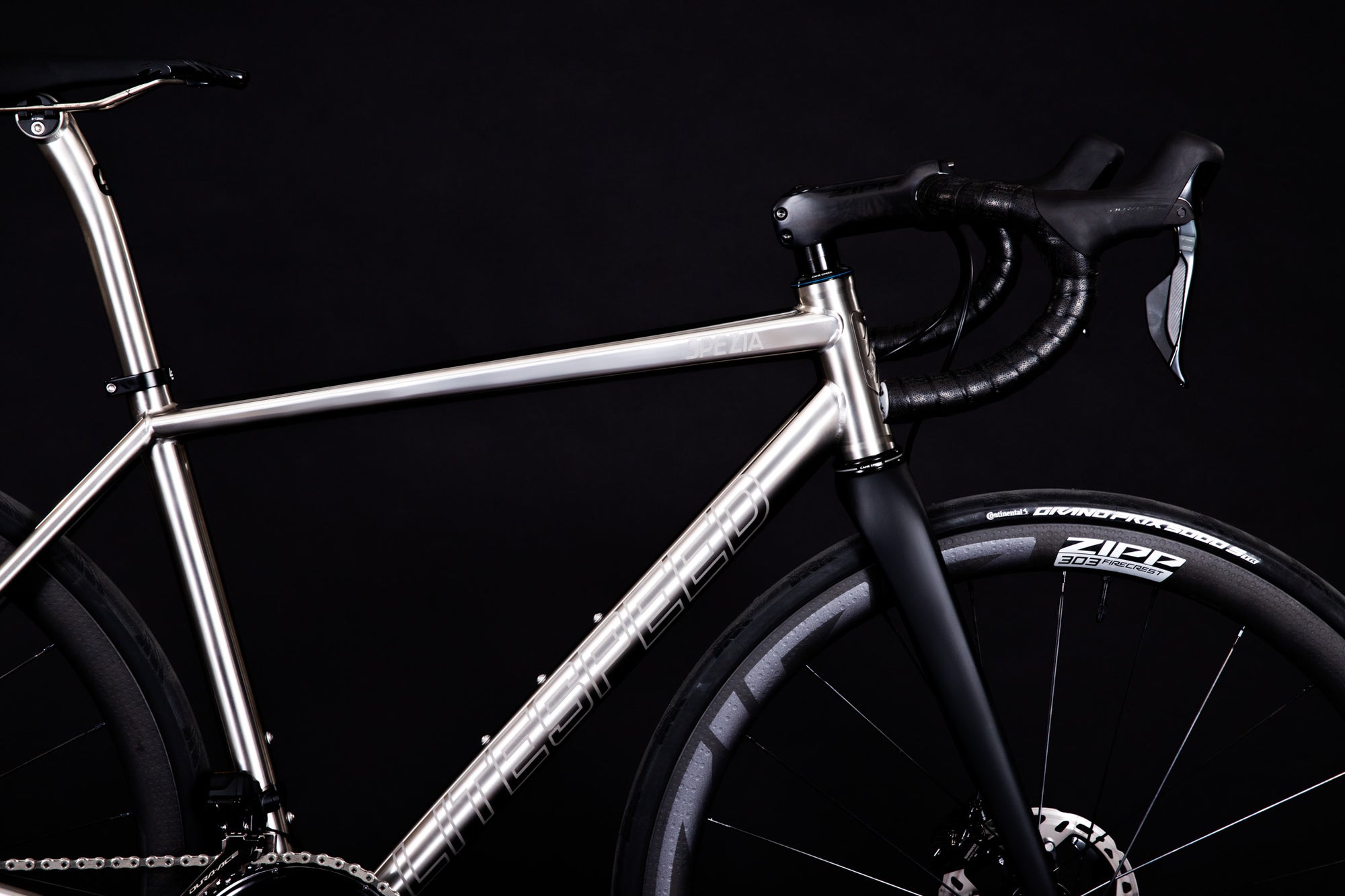 Silver bicycle frame with black components on a dark background